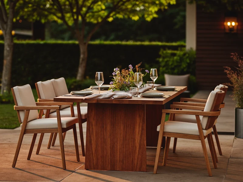Abendliche Gartenterrasse mit gedecktem Teak-Esstisch im warmen Laternenlicht