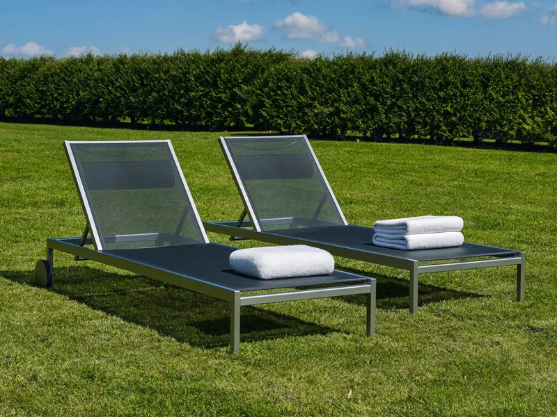 Illustration zweier Aluminium-Sonnenliegen auf einem Rasen neben einer Hecke