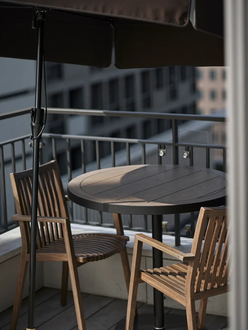 Illustration eines Ampelschirms über einem Bistrotisch mit zwei Stühlen auf einem Balkon